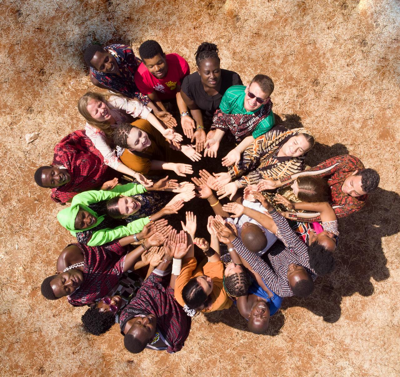 services-03 Aerial view of a diverse group in Tanzania symbolizing unity and teamwork by joining hands.