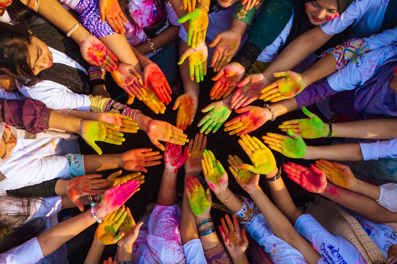 gallery-6 Vibrant top view of diverse hands united in colorful Holi celebration.